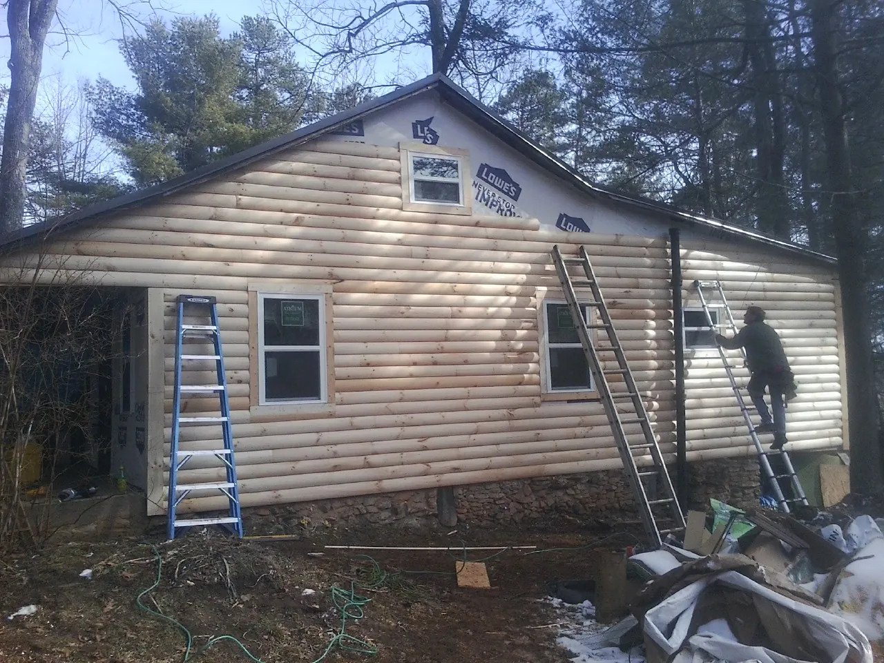 Ladders set against fresh log siding during an exterior remodel in Aurora